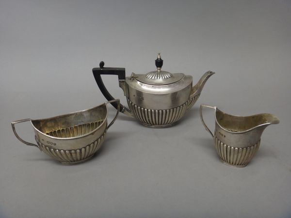 A late Victorian silver composite three piece tea set, comprising; a teapot, a twin handled sugar bowl and a milk jug, each piece of oval form, with p