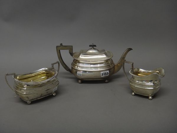 A silver three piece tea set, comprising; a teapot, a twin handled sugar bowl and a milk jug, each piece of curved rectangular form, raised on four sp