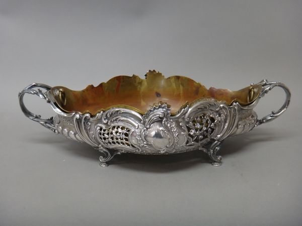 A French twin handled table centrepiece bowl, of shaped oval form, with scroll and floral embossed and pierced decoration, raised on four scroll pierc