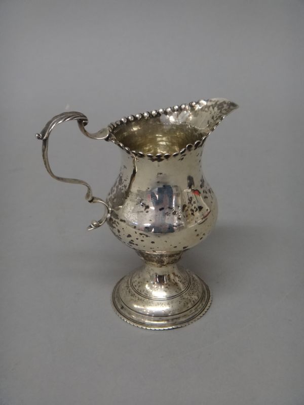 A George III silver cream jug, of inverted pear shaped form, with a scrolling handle, on a circular foot, London 1775, weight 73 gms.