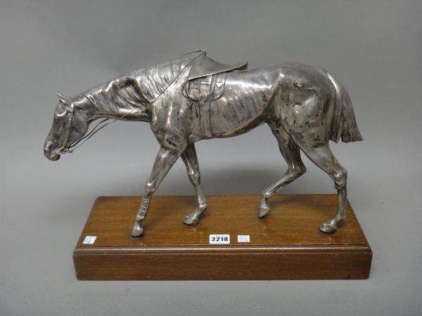 A plated model of a walking horse raised on a rectangular wooden base, height 26cm, and a plated tantalus stand, with two associated faceted square gl