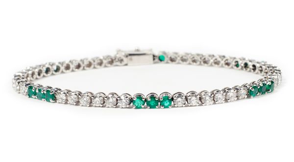 A platinum, emerald and diamond tennis bracelet, mounted with six rows of six circular cut diamonds, alternating with six rows of three circular cut e