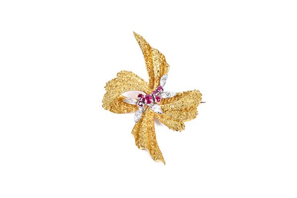 An 18ct gold, ruby and diamond set brooch, designed as a bow, with a cast and textured finish, the centre with a spray motif, mounted with circular cu