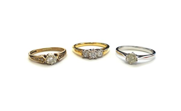 An 18ct gold and diamond set three stone ring, claw set with a row of circular cut diamonds, a 9ct white gold and diamond single stone ring and a 9ct