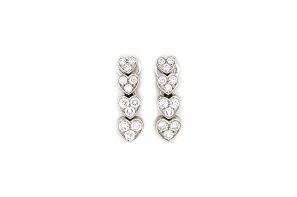 A pair of 18ct white gold and diamond set earclips, 2004, each formed as a row of four graduated diamond three stone heart shaped motifs, mounted with