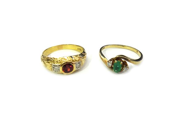 A 9ct gold, emerald and diamond three stone ring, claw set with the oval cut emerald between two circular cut diamonds, in a crossover design, ring si