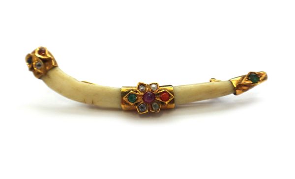 A gold and gemstone mounted bone brooch, mounted with a cabochon ruby, two circular cut emeralds and with further gems, length 7.3cm, with a case.