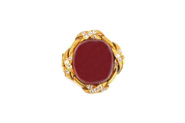 A gold, carbuncle garnet and diamond set brooch, mounted with a large oval carbuncle garnet at the centre and with four diamond set crossover motifs,