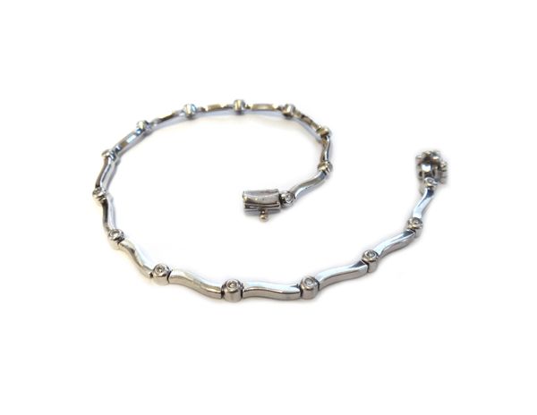 A 9ct white gold and diamond bracelet, in a serpentine link design, collet set with circular cut diamonds at intervals, on a snap clasp, length 19cm,