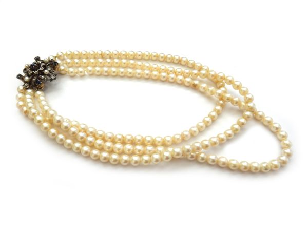 A three necklace of uniform cultured pearls, on a diamond, sapphire and cultured pearl clasp, approximate length of necklace 36 cm.