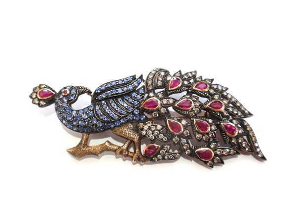 A diamond, ruby and sapphire set brooch, designed as an exotic bird on a branch, mounted with circular cut diamonds, pear shaped rubies and with small