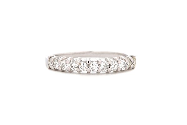 An eleven stone diamond set half hoop eternity ring, claw set in white metal, stamped 18 CT, ring size O, gross weight 2.3 gms.   Illustrated