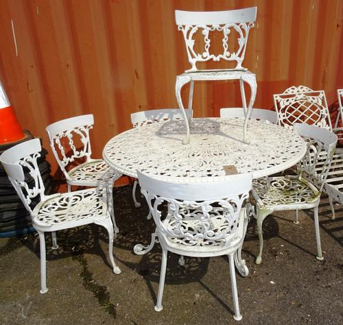 A 20th century white painted metal circular garden table, 120cm wide x 72cm high, with a set of seven chairs, (8).  OUT