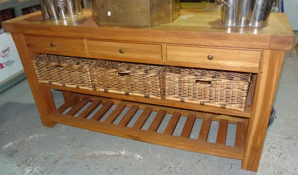 A 20th century oak sideboard, with three drawers and a two tier shelf, with three wicker baskets, on block supports, 180cm wide x 92cm high x 48cm dee