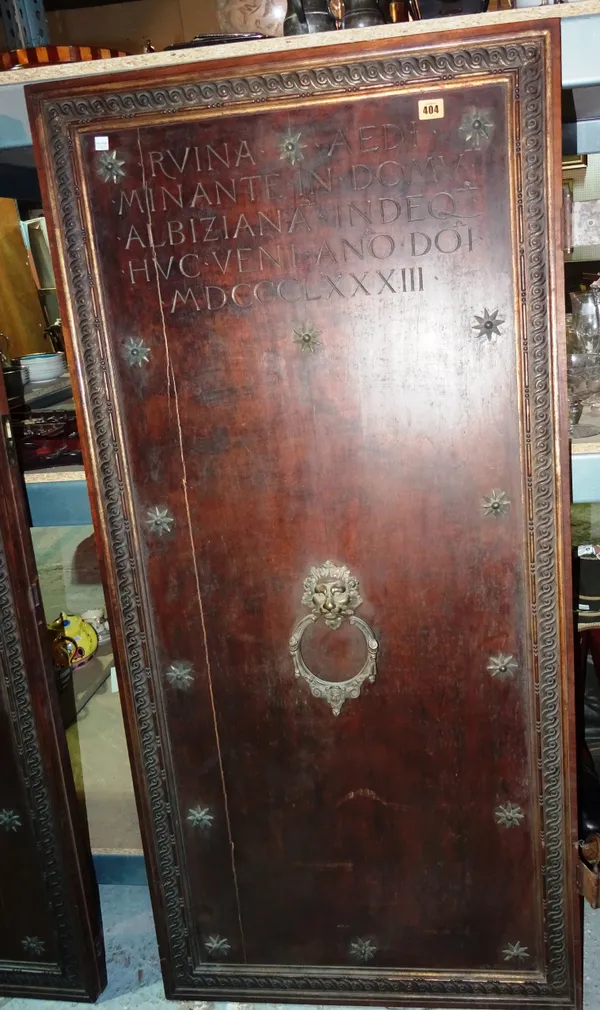 A pair of early 20th century Italian walnut doors, each with carved Latin text, gilt metal star mounts and lion head knockers, with scrolling carved b