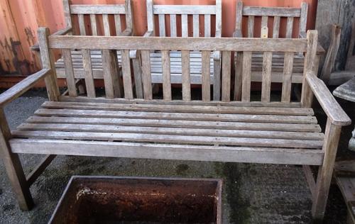 A 20th century hardwood garden table, on trestle supports, 140cm wide x 74cm high, together with a set of three matching open armchairs and a bench, (