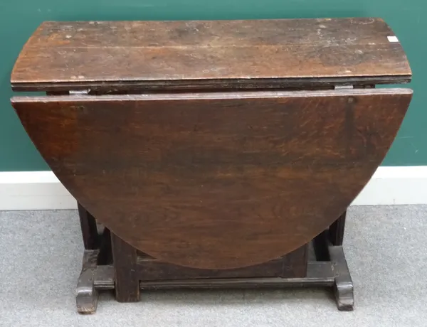 A 17th century oak gateleg dining table, with oval drop flap top, on slab supports and double stretcher, 47cm across x 150cm across open and 99cm wide