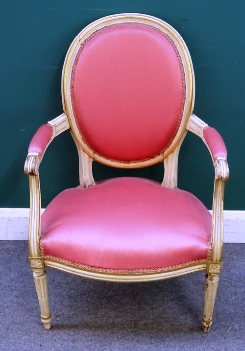 A cream and gilt decorated armchair, in the mid-George III style, the oval back, arms and seat with coral pink upholstery, within moulded frame, carve