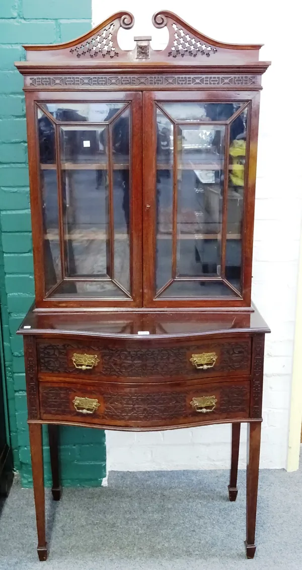 James Shoolbred & Co; an Edwardian blind fret-work mahogany display cabinet on two drawer stand, with pierced scrolling swan neck pediment on square t
