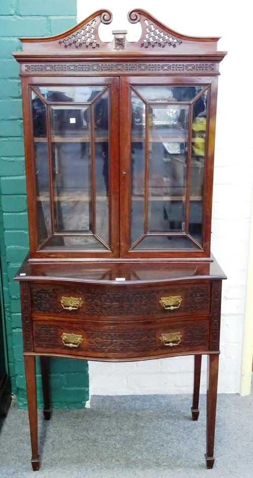 James Shoolbred & Co; an Edwardian blind fret-work mahogany display cabinet on two drawer stand, with pierced scrolling swan neck pediment on square t