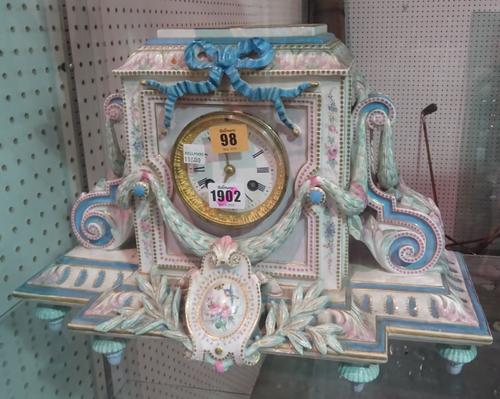 A Paris porcelain mantel clock, circa 1878, the breakfront foliate case enclosing a two train movement with hammer striking a bell, 29cm high. (a.f).