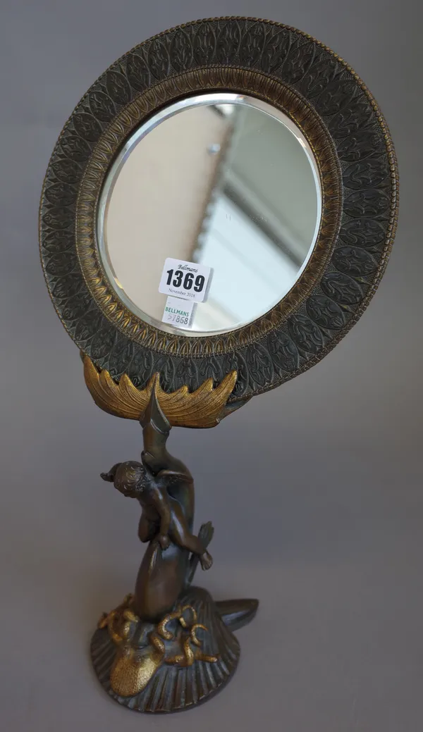 A 19th century French gilt and patinated bronze figural table mirror, the foliate cast circular frame held aloft by a cherub riding a mythological dol