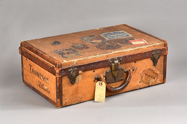 A Louis Vuitton leather and canvas bound suitcase, early 20th century, with stamped brass hardware and remnants of original travel labels, detailed in