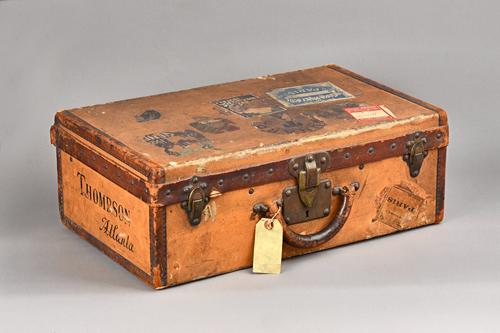 A Louis Vuitton leather and canvas bound suitcase, early 20th century, with stamped brass hardware and remnants of original travel labels, detailed in