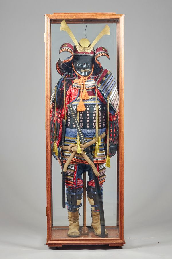 A Japanese samurai suit of armour, late 20th century, with sword, displayed in a case, case 197cm high.  Illustrated.