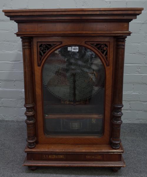 A Swiss walnut cased polyphon, late 19th century, the glazed door containing a coin operated mechanical movement and 15.5inch steel disc, gilt lettere