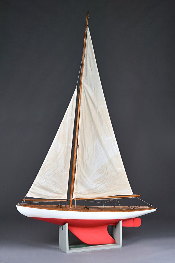 A 20th century wooden pond yacht, fully rigged over a planked deck and two tone grey/red hull, on a wooden stand, yacht 197cm high. Illustrated. A/S