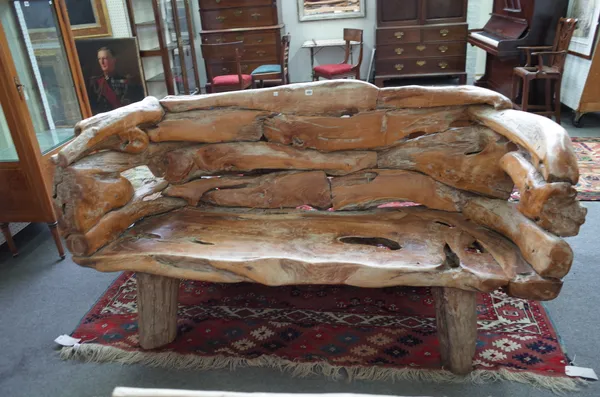 A wooden bench of naturalistic driftwood form on four shaped legs, 178cm wide.