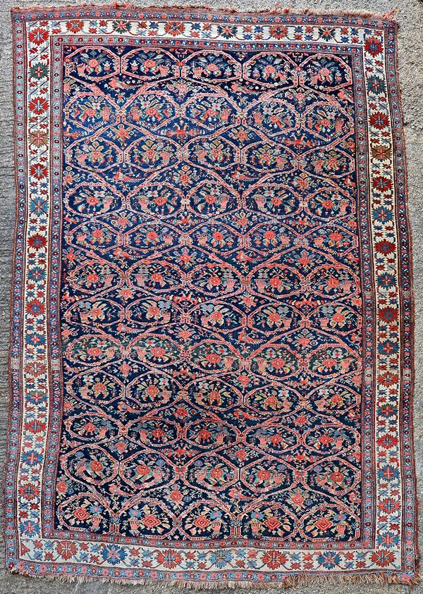 A Bidjar carpet, Persian, the dark indigo field with a trellis pattern, with each section bearing a hand holding a flower or spray of flowers; a singl