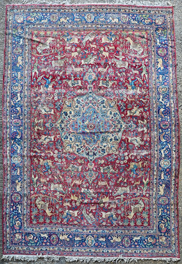A Tehran carpet Persian, the madder field with a bold ivory and pale indigo medallion, allover with hunting scenes with various figures and animals, a