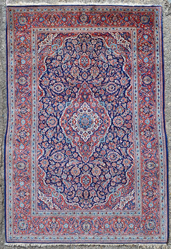 A Kashan rug, Persian, the indigo field with a madder medallion, matching spandrels allover with intricate floral sprays; a madder palmette, leaf and