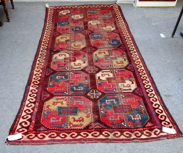 AFTERSALE An Uzbek main carpet, the madder field with two columns of zix bold guls, supporting cross border, 298cm x 144cm.
