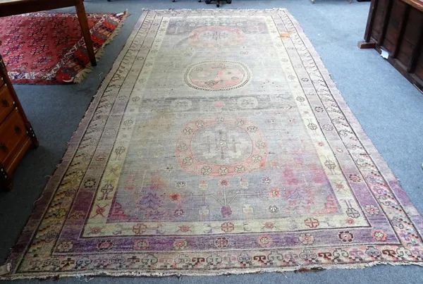 A Khotan carpet, the faded purple field with three bold roundels, supported by stylised plants and flowers, 410 x 220cm. Provenance; Sir Henry Norman,