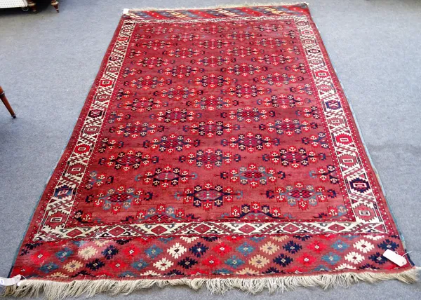 A Yomut carpet, the madder field with diagonal rows of bold yomut guls, an ivory rosette and waved hooked vine border, 315 x 214cm.