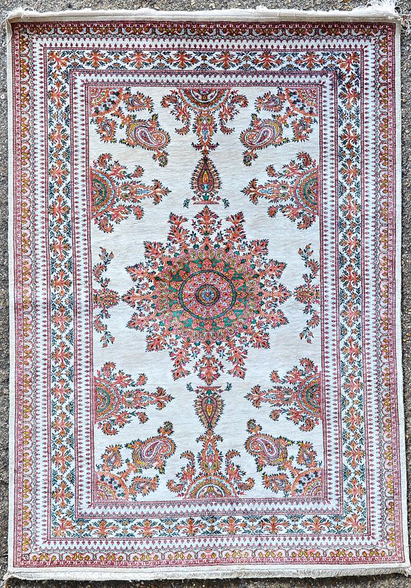 A silk Isfahan rug, Persian, the ivory field with an intricate 'paisley' design medallion, boteh spandrels and matching side medallions, a complementa
