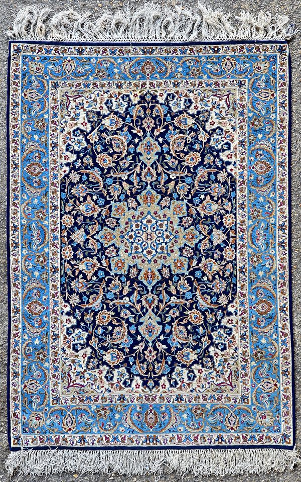 A Nain rug, Persian, the dark indigo field with a faceted olive medallion, ivory spandrels, all with intricate floral sprays, a pale indigo palmette,