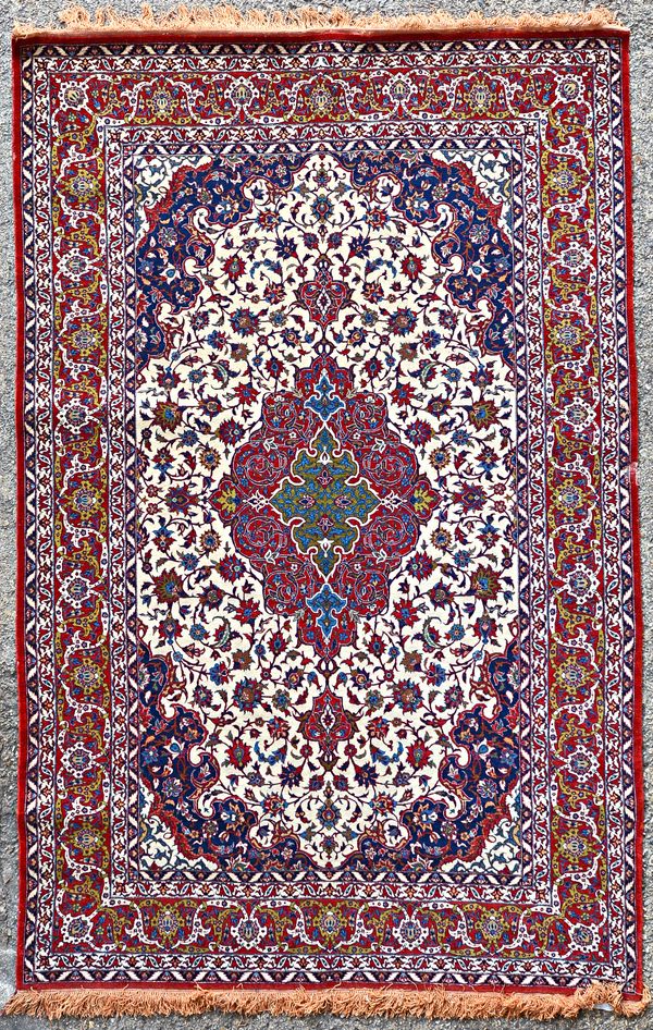 A fine Tehran rug, Persian, the ivory field with a madder and olive medallion indigo spandrels, all with intricate floral sprays, a madder palmette an