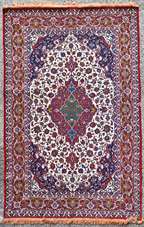 A fine Tehran rug, Persian, the ivory field with a madder and olive medallion indigo spandrels, all with intricate floral sprays, a madder palmette an