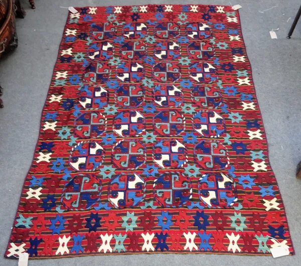 An Uzbek embroidered kelim, the madder striped field with bold stylised guls, supporting stars and star border, 254 x 177cm.