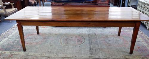 A 19th century French cherry wood kitchen table, the cleated plank top over plain frieze, on tapering square supports, 109cm wide x 275cm long x 77cm