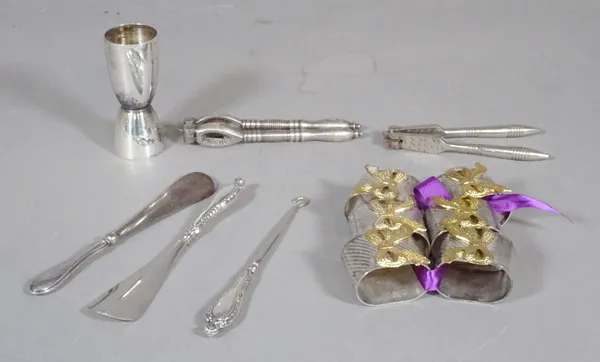 A group of silver plated items to include napkin rings, two pairs of nutcrackers, two silver plated shoe horns, a shot measure and a button hook, (qty