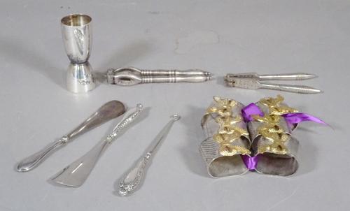 A group of silver plated items to include napkin rings, two pairs of nutcrackers, two silver plated shoe horns, a shot measure and a button hook, (qty
