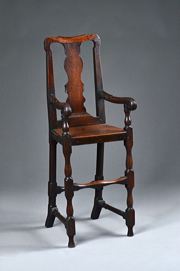 An 18th century oak child's high chair with vase splat back and carved arms on block and turned supports, 42cm wide x 112cm high. Illustrated.
