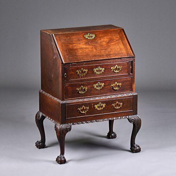 A mid-18th century mahogany dressing bureau on stand, the fall over two long drawers, one with fitted interior, the gadrooned and floral carved base o
