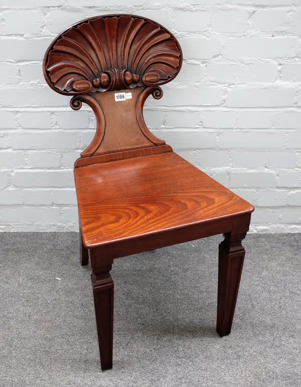 A 19th century mahogany hall chair, with deep carved shell back over solid seat, on tapering square supports, 43cm wide x 82cm high.