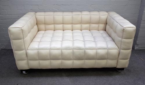 A 20th century cream leather square back sofa with piped cube pattern upholstery on ebonised bracket feet, 150cm wide x 72cm high x 80cm deep.